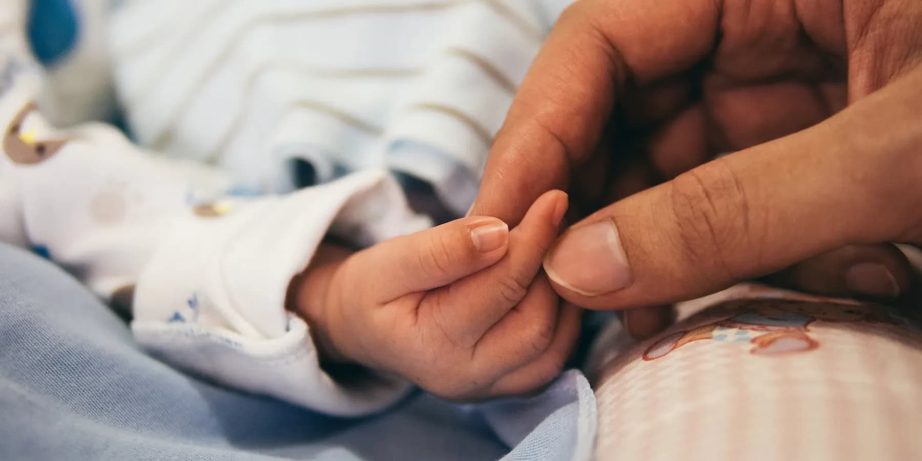 A close-up photo of mother and baby hands in a calm home setting